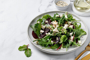 Healthy vegetarian salad with beet, mix salad leaves, feta cheese, nuts. Meal healthy snack copy space for text. On marble white background.
