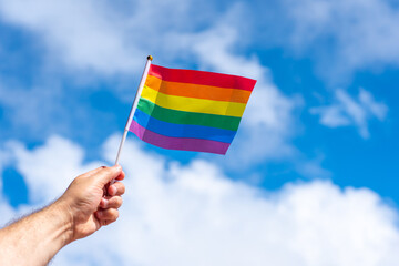 Unfurled small LGBT flag in a male hand