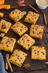 Pumpkin blondie or cake with chocolate drops, walnuts, cinnamon and anise on a dark wooden background. Dessert for Thanksgiving or Halloween.