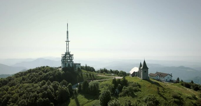 Aerial panoramic shot of dron around the hill Kum with church and tower on him in Slovenia.