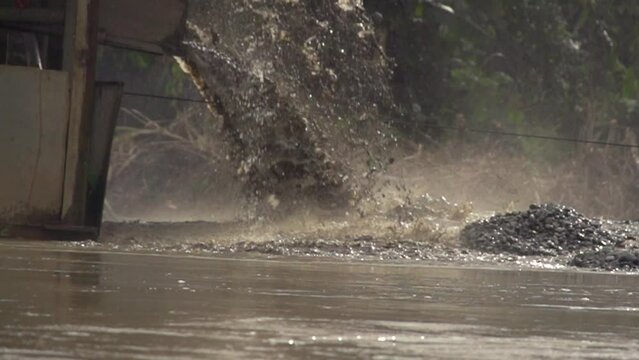 Processed sand spewing out of a gold dredger in to the river in Checo, Colombia. Slow motion.