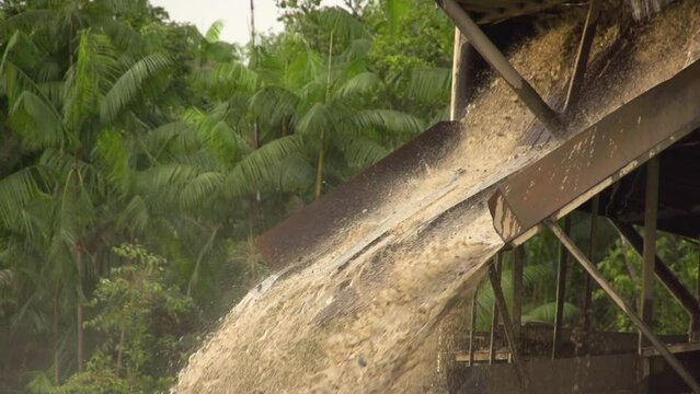 Processed sand and mud spewing out of a gold dredger in to the river in Checo, Colombia. Slow motion.