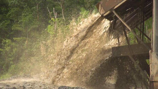 Processed sand and mud spewing out of a gold dredger in to the river in Checo, Colombia. Slow motion.