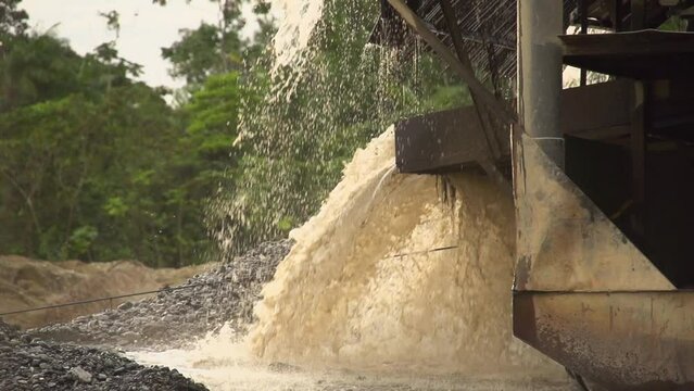 Processed sand and mud spewing out of a gold dredger in to the river in Checo, Colombia. Slow motion.