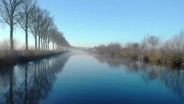 Drone shot dolly forward juste above de water on the Scheldt river next Escanaffles in the morning with smog and nice light