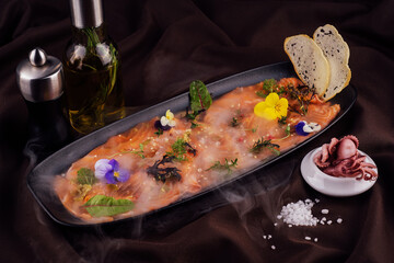 Smoked salmon carpaccio and octopus with white smoke of liquid nitrogen