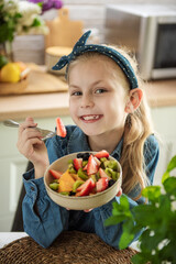 Cute little girl eats fruit salad