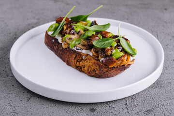 Toast with fried porcini mushrooms on white plate