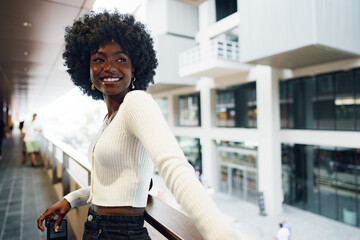 Portrait of young african woman with afro hairstyle standing at balcony and posing.