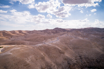 Fototapeta na wymiar Desert in Israel. Mountains and Road in Background. Sandy Surface. Drone Point of View.