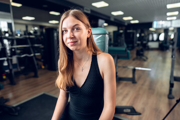 Fototapeta premium Smiling teen girl training in a fitness club