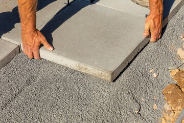 Worker  places the tile exactly at the bed of small paving stones