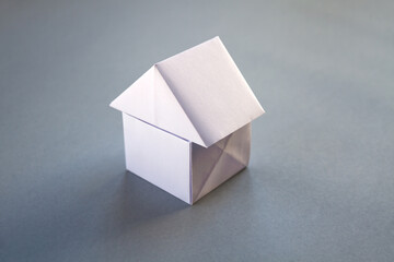 White paper house origami isolated on a grey background