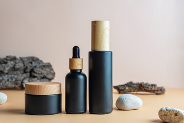 Set of natural cosmetics in black matte glass package on beige background with bark of the tree and...