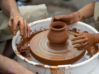 The potter teaches a young student.