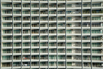 Fototapeta na wymiar Facade of modern white apartment building that balance with a lot of windows and terrace on row.