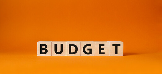 Budget symbol. Concept word Budget on wooden cubes. Beautiful orange background. Business and Budget concept. Copy space.