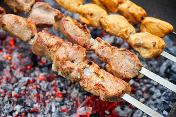 Pork and chicken skewers are fried on skewers on the grill