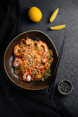 Stir fry noodles with vegetables and shrimps in black bowl