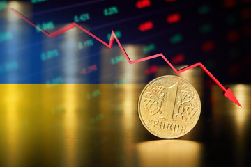One Ukrainian hryvnia coin on the background of stacks of coins and Falling stock market chart and Ukrainian flag
