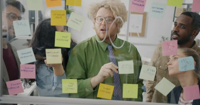 Portrait of businesspeople diverse team working with glass board writing on sticky notes brainstorming together. Creative thinking and people concept.