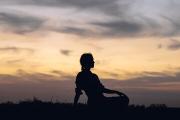 silhouette of a young girl on the background of the sunset sky
