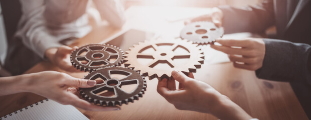 Group of people working in the office while putting together cogwheels.