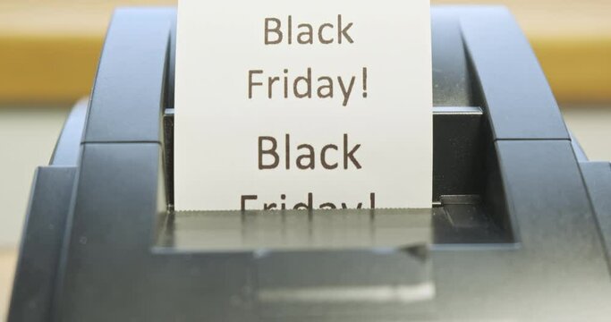 Receipt printer prints text: Black Friday. Close-up, front view. Concept of promotions, sales in stores. Tear off the check