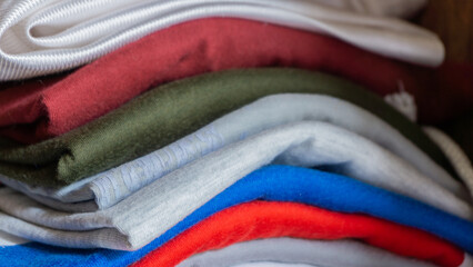 Stack of clothes in wardrobe. stack of colorful folded clothing items. household concept. Clean...