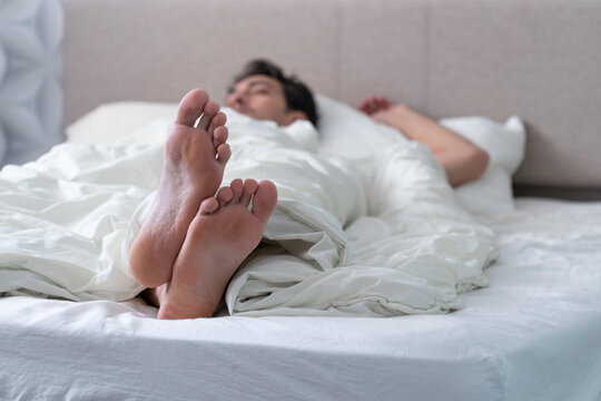 Close up photo of male feet while sleeping in the bed at the morning time