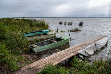 Fototapeta na wymiar boats for fishing on the lake on a cloudy autumn day