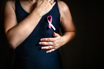 October is breast cancer awareness month,a woman holds a pink ribbon to support people living and...