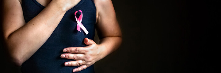 October is breast cancer awareness month,a woman holds a pink ribbon to support people living and...