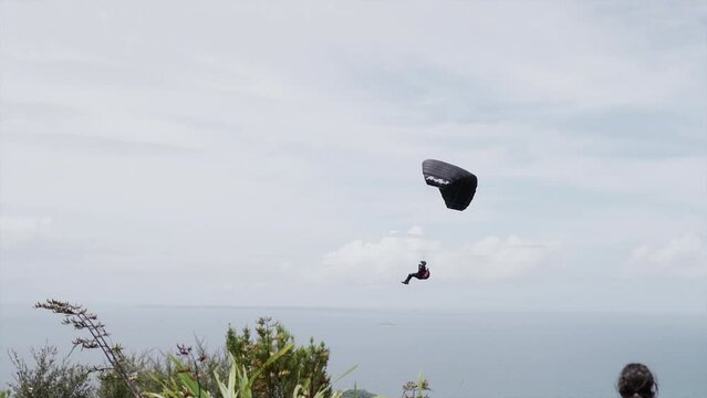 Man Paragliding While Woman Watches Him As He Does On Mount Maunganui 