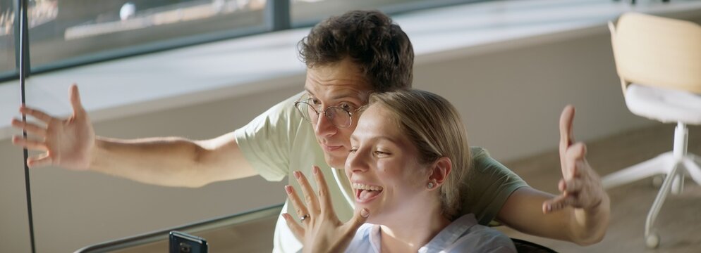  Young couple announcing their engagement to friends or family during video call, bride-to-be showing her ring finger to a phone camera - Powered by Adobe