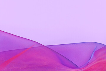 Pink and purple tulle netting fabric with blue hue at bottom of pink background with copy space