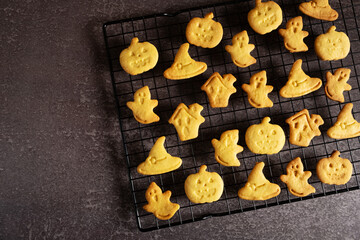 Halloween cookies in the form of a pumpkin, a witch's hat, a ghost and a terrible house on a black grate for baking