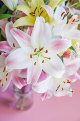 Obraz na płótnie Canvas Bouquet white flowers lilies on a pink background with space for text. Top view, flat lay. Composition with beautiful blooming lily flowers on color background