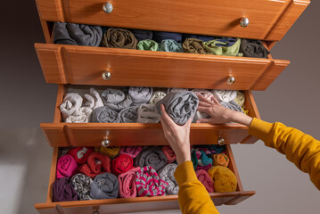 Cleaning and sorting clothes in the wardrobe Japanese method. Open chest drawers with  vertical storaged twisting clothes. View from above.