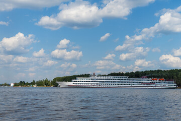 Pleasure 4-deck ship sails next to the river bank.