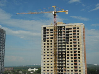 Fototapeta na wymiar Crane and building under construction against blue sky