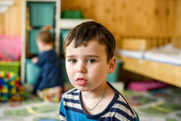 A little boy in the nursery and a little sister in the background.