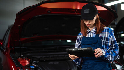 Fototapeta na wymiar Caucasian female auto mechanic uses a special computer to diagnose faults. 