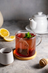 Cup of tea in glass mug with lemon, honey and mint leaves. Lifestyle warm drink. Relaxation concept.