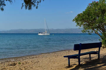 seascape with a yacht and a wooden bench on the shore