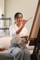 Pleasant young woman painting picture with watercolor at cozy home. Art, creative hobby and leisure activity concept