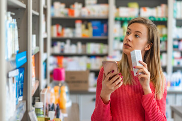 Woman uses smart phone while in pharmacy. They have the best medicine here. They have so much on...