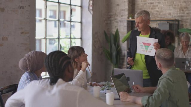 senior manager showing sales process and amount potential revenue using funnel chart to multicultural young creative employees