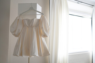 short wedding dress. wedding dress hanging on a floor lamp