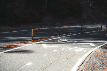 View with a shallow depth of field of a modern suburban road in a park around Lisbon with bicycle marking and two lanes of opposite directions, and dividing road bollards with a reflective coating